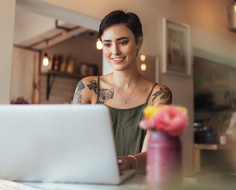 smiling person sending a message to a friend on laptop