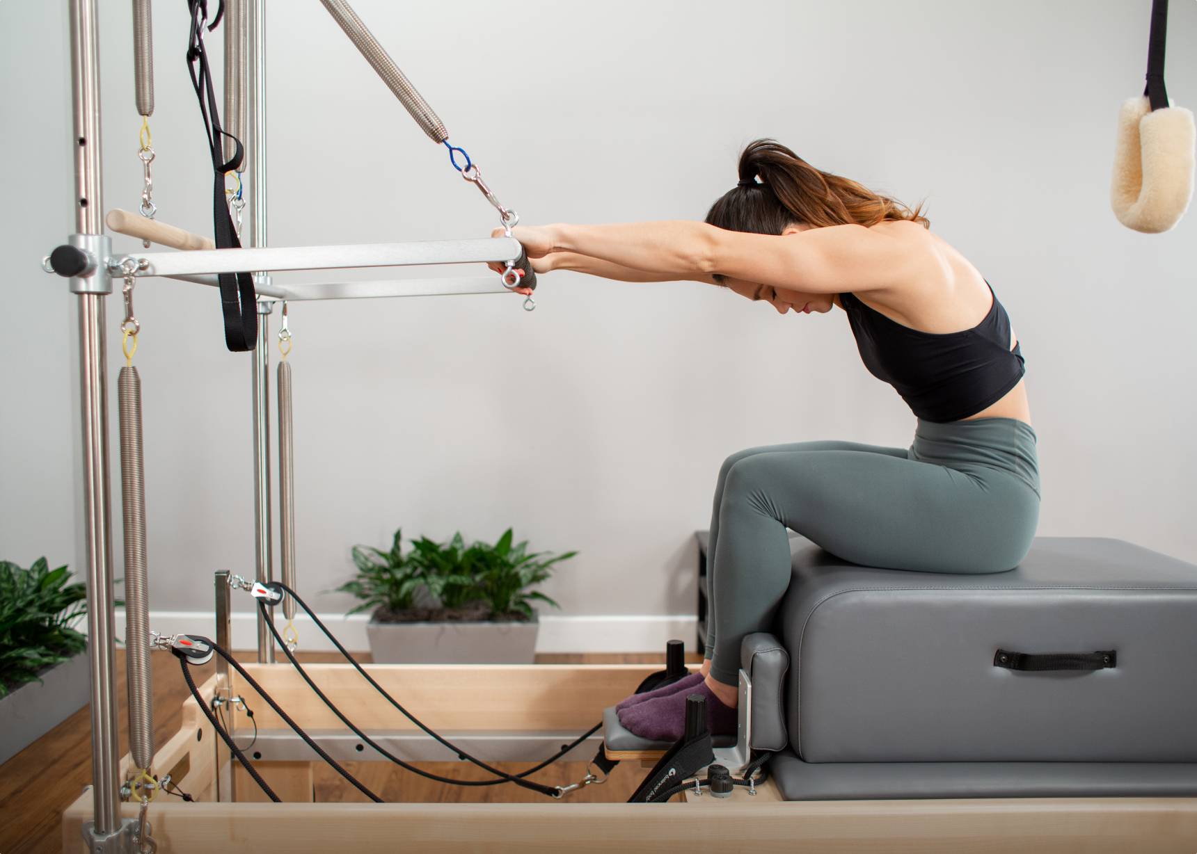 Woman utilizing reformer and trapeze for strength and flexibility training 