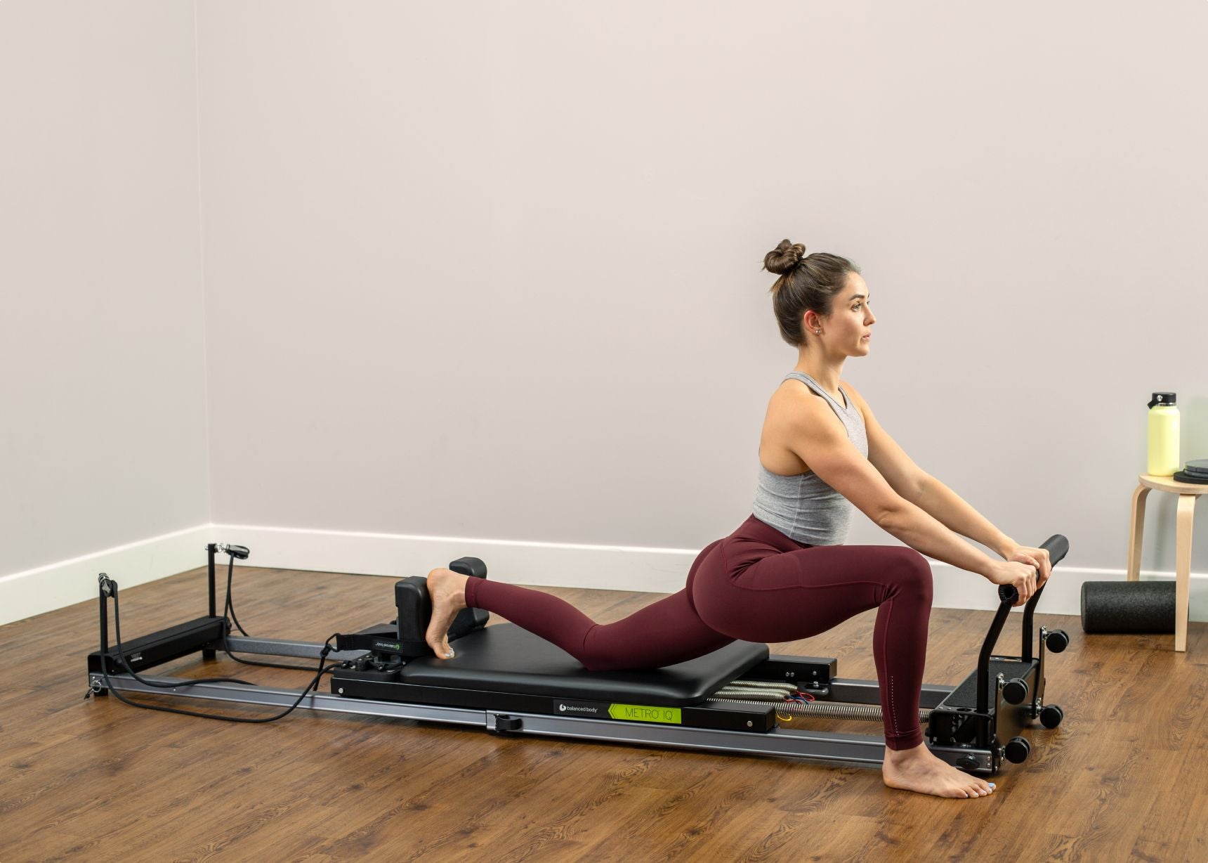 Female practitioner using Metro IQ Pilates Reformer machine for a Pilates workout session.
