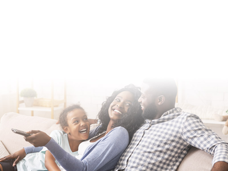 smiling family watching TV on couch