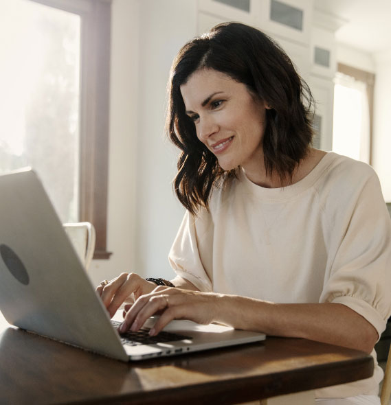 person smiling as they type an email on their laptop