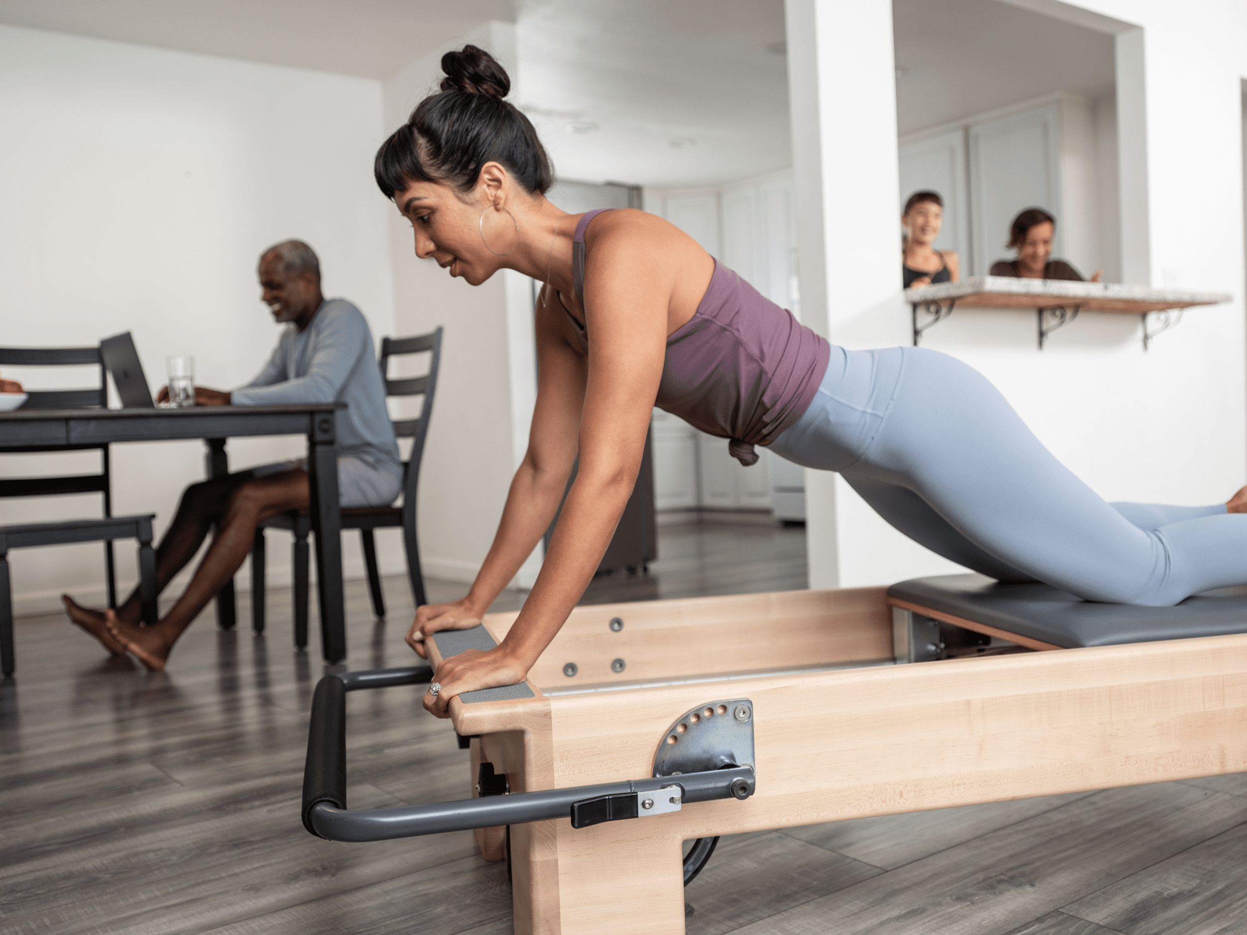 Woman demonstrating a controlled Pilates movement on a Pilates Studio Reformer, highlighting her core stability and precise alignment.