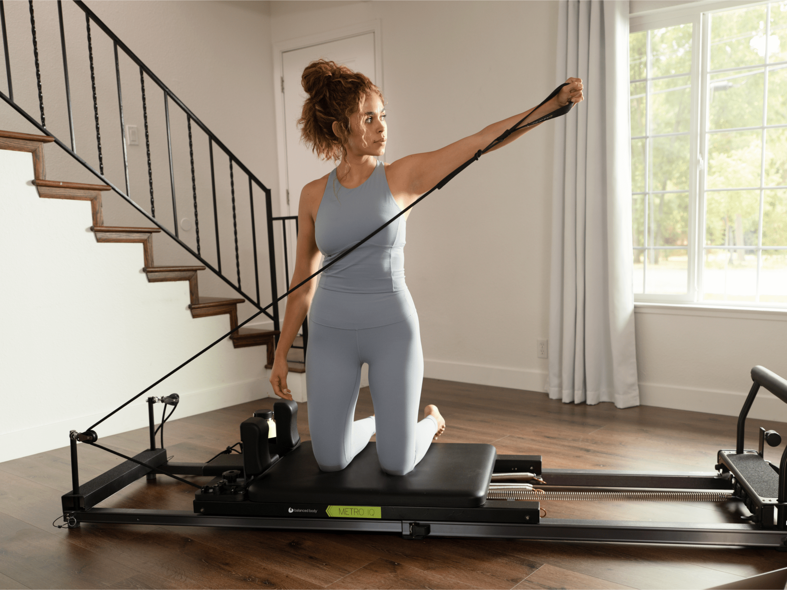 Woman performing an exercise on a Metro-IQ Pilates Reformer, focusing on her posture and alignment.