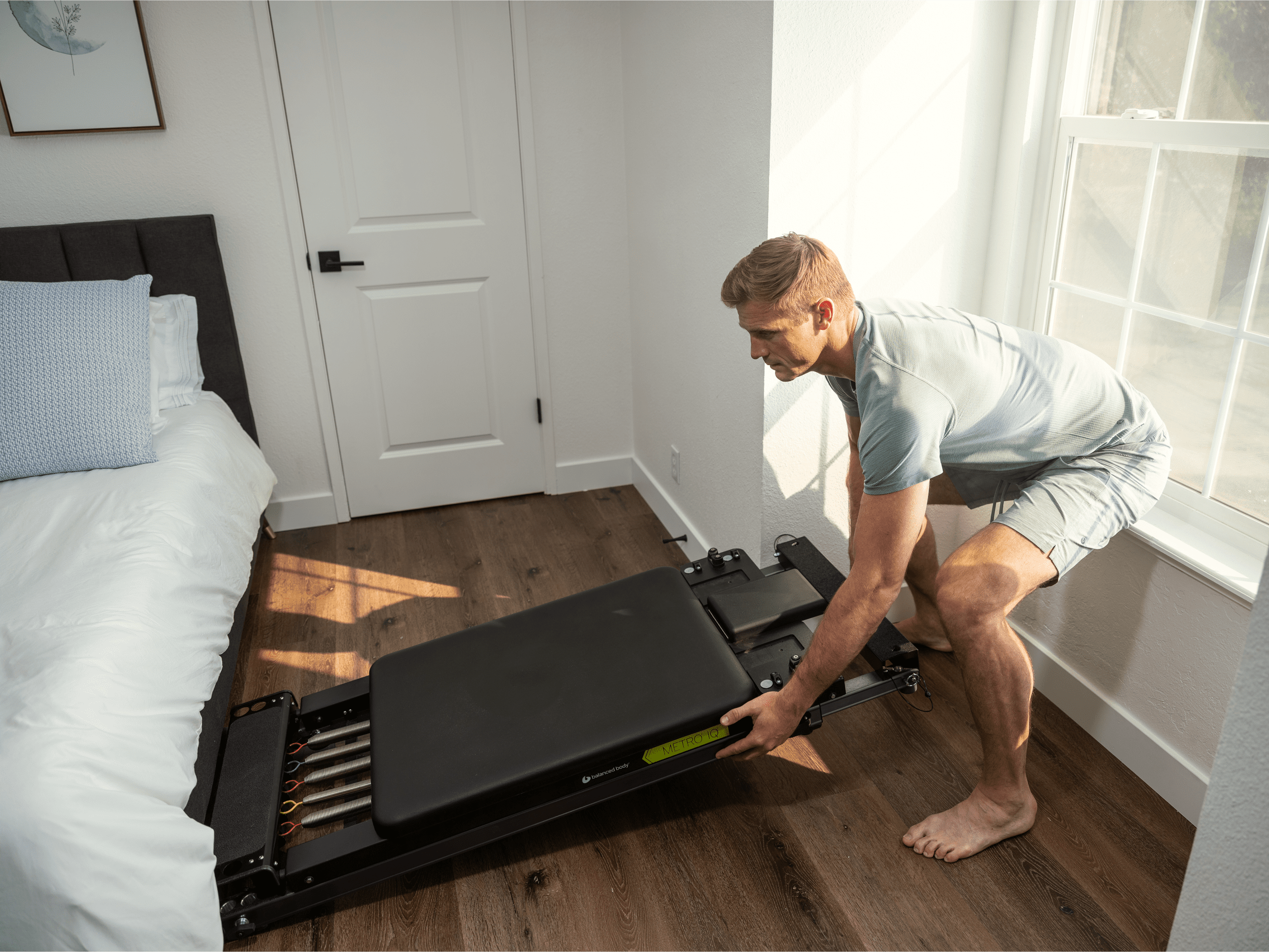 A man is storing a Metro-IQ Pilates Reformer.