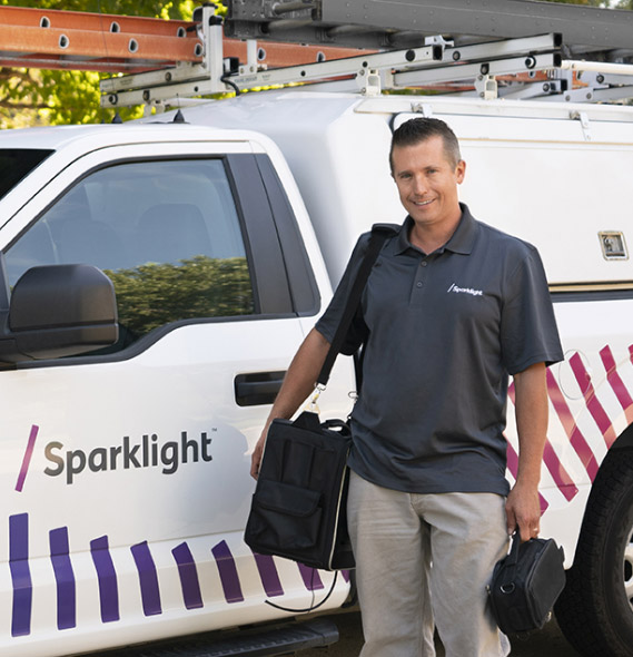 A smiling Sparklight associate by a Sparklight truck